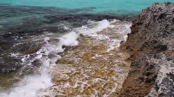 Лазурне море, море берга кольорове, хвилі ламаються на скелястому березі, на тлі берегової лінії — стокове відео