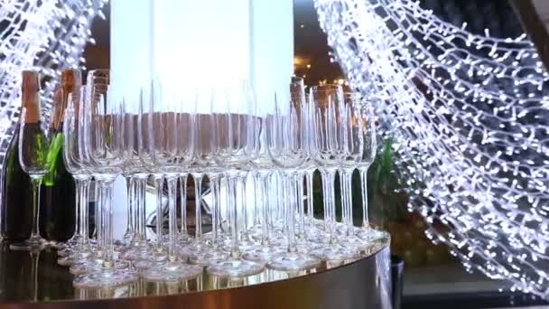 Очки на столе "шведский стол", бутылка шампанского, дизайн ресторана, интерьер, внутри помещения, плавное движение камеры вдоль стола, ряды бокалов вина на столе, мелкая глубина резкости — стоковое видео