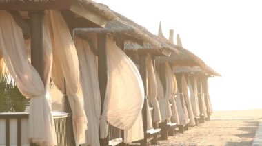 Sandy Beach ile Thatched şemsiye üzerinde A rüzgarlı gün, okyanus plaj şemsiyeleri