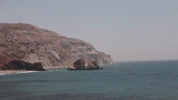 La montagna lasciando in mare, La costa del mare con rocce, cielo blu, spiaggia di sabbia, onde marine, Grecia, Cipro, piscina di Afrodite, bellissimo paesaggio maestoso, spiaggia rocciosa alte scogliere cielo blu e mare — Video Stock