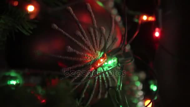 Arbre de Noël avec jouets, une guirlande électrique est sur le sapin, boule de Noël rouge, gros plan — Video