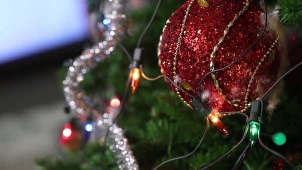 Árbol de Navidad con juguetes, una guirnalda eléctrica está en el árbol, bola roja de Navidad, primer plano — Vídeos de Stock