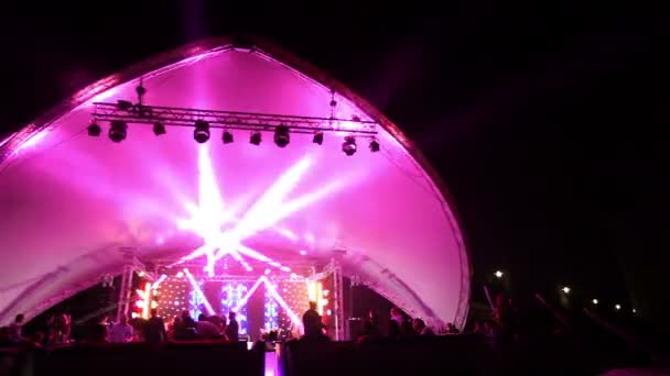 Palco e uma discoteca na praia. Night Beach Disco com iluminação. concerto. Celebração. Férias. Festa. Dançando pessoas com alegria divertida no entretenimento discoteca. praia arenosa — Vídeo de Stock