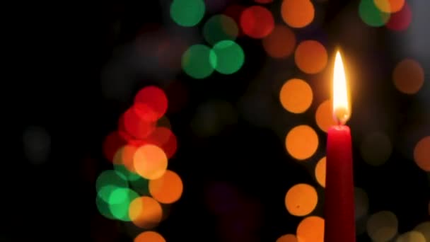 Rode kaars op een donkere achtergrond, Kerstmis kaars op bokeh licht achtergrond, avond van Kerstmis, Nieuwjaar, Kerstmis, gekleurde cirkels, bokeh, close-up — Stockvideo