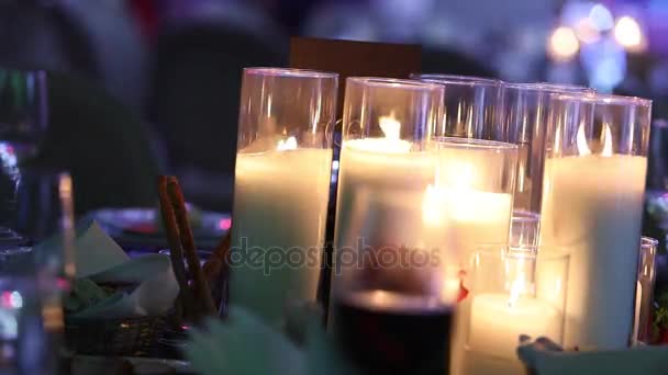 Velas decorativas en la mesa de comedor, vasos y velas de Navidad en la mesa, velas de cera blanca con candelero de vidrio, vela con candelero de vidrio, restaurante, interior, primer plano — Vídeo de stock