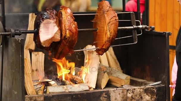 Grandes trozos de deliciosos jamones de cerdo cocinados en una fogata. La comida callejera. Comida al aire libre. Acampar y cocinar en una saliva sobre el fuego, el hombre cocina grandes trozos de carne en una saliva en el fuego, primer plano — Vídeos de Stock