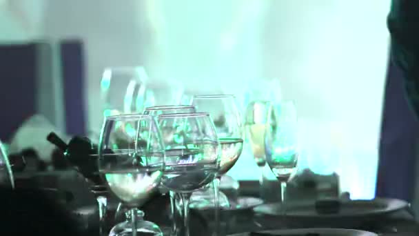 Glas van de bril op een tafel in een restaurant, podium verlichting, op de achtergrond, donkere, ondiepe scherptediepte, close-up — Stockvideo