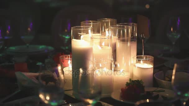 Velas decorativas na mesa de jantar, óculos e velas de Natal na mesa, velas de cera branca com castiçal de vidro, vela com castiçal de vidro, restaurante, interior, close-up — Vídeo de Stock