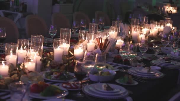 Velas decorativas en la mesa de comedor, vasos y velas de Navidad en la mesa, velas de cera blanca con candelero de vidrio, vela con candelero de vidrio, restaurante, interior, primer plano — Vídeo de stock