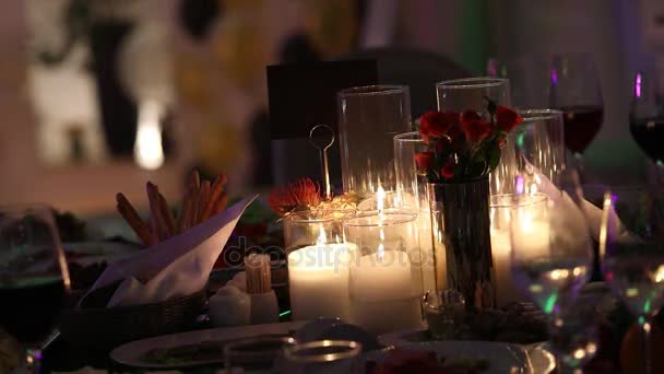 Velas decorativas en la mesa de comedor, vasos y velas de Navidad en la mesa, velas de cera blanca con candelero de vidrio, vela con candelero de vidrio, restaurante, interior, primer plano — Vídeos de Stock