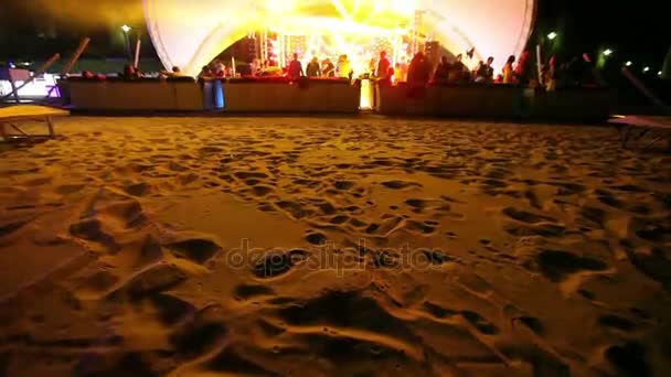 Stage and a disco on the beach. Night Beach Disco with illumination. concert. Celebration. holiday. feast. Dancing people with fun gladness on the discotheque entertainment. sandy beach — Stock Video