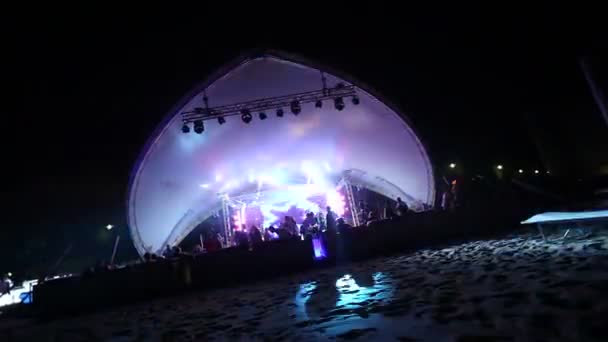 Сцена и дискотека на пляже. Ночная пляжная дискотека с подсветкой. концерт. Празднование. праздник. пир. Танцующие люди с веселой радостью на дискотеке развлечений. песчаный пляж — стоковое видео