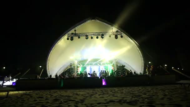 Stage and a disco on the beach. Night Beach Disco with illumination. concert. Celebration. holiday. feast. Dancing people with fun gladness on the discotheque entertainment. sandy beach — Stock Video