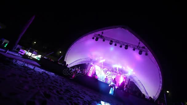 Palco e uma discoteca na praia. Night Beach Disco com iluminação. concerto. Celebração. Férias. Festa. Dançando pessoas com alegria divertida no entretenimento discoteca. praia arenosa — Vídeo de Stock