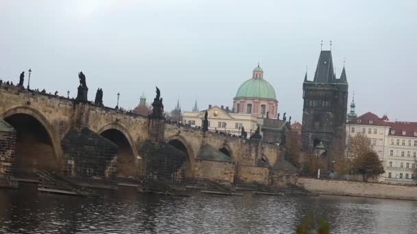 The Charles Bridge on the background of the old tower and the green dome of the cathedral in Prague, side view, tourists stroll along the Charles Bridge, Prague, October 19, 2017 — Stock Video