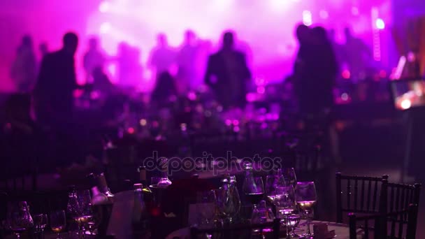Ένα πάρτι νεολαίας σε ένα εστιατόριο ή ένα νυχτερινό κέντρο διασκέδασης, Συμποσίου πίνακες με αλκοόλ και τρόφιμα φόντο σιλουέτες χορό ανθρώπους, στάδιο φως και μωβ γεμίσματος — Αρχείο Βίντεο