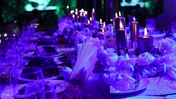 A tábla, a szemüveg és a karácsonyi gyertyák tábla, esküvői dekoráció, fehér viasz candleswith üveg gyertyatartó, dekoratív gyertyák gyertya, üveg gyertyatartó, étterem, belső, közeli — Stock videók