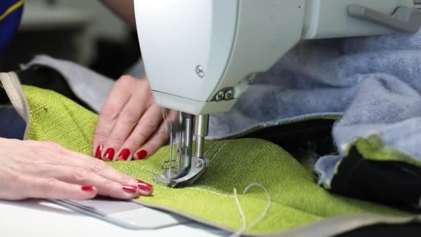 Vrouw die werkt aan een naaimachine, twee-naald naaien machine, rode manicure op vrouwelijke handen, Slow Motion Video, close-up, ondiepe scherptediepte — Stockvideo