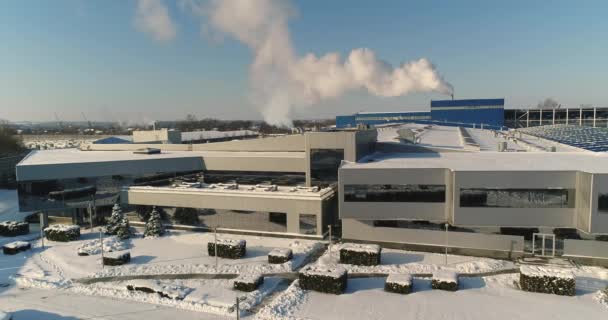 En modern fabrik eller kommersiell byggnad, utsidan av en modern fabrik eller anläggning, bygga fasad och bilparkering och panoramautsikt från luften, vintertid, solig dag, blå himmel — Stockvideo