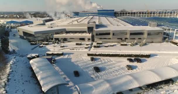 En modern fabrik eller kommersiell byggnad, utsidan av en modern fabrik eller anläggning, bygga fasad och bilparkering och panoramautsikt från luften, vintertid, solig dag, blå himmel — Stockvideo