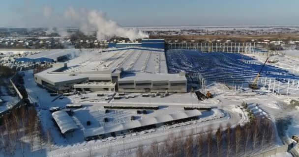 Een moderne fabriek of commerciële gebouw, de buitenkant van een moderne fabriek of fabriek, bouw van de gevel en de auto parkeren, panoramisch uitzicht vanuit de lucht, wintertijd, zonnige dag, blauwe hemel — Stockvideo