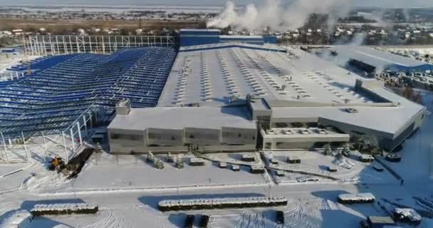 Ein modernes Fabrik- oder Geschäftshaus, das Äußere einer modernen Fabrik oder Anlage, Gebäudefassade und Parkplatz, Panoramablick aus der Luft, Winterzeit, sonniger Tag, blauer Himmel — Stockvideo