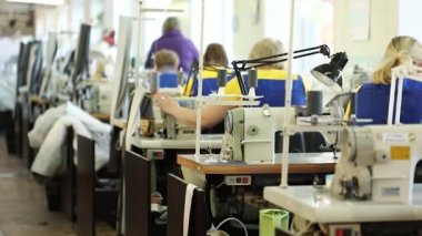 Çalışan bir dikiş makinesi, endüstriyel boyutu tekstil fabrikası, işçilerin üretim hattı, sanayi iç, iğne dikiş makinesi, sığ derinlik-in tarla, kadın