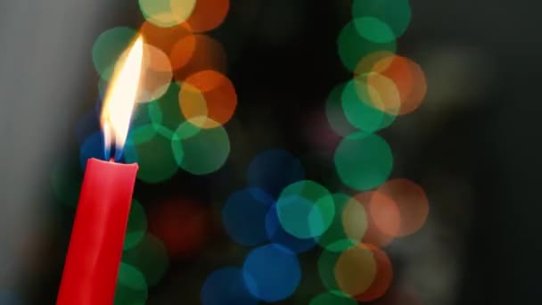 Red candle on a dark background, Christmas candle on bokeh lights background, Christmas evening, New Year, xmas, colored circles, bokeh, closeup — Stock Video
