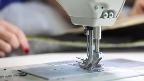 Mulher trabalhando em uma máquina de costura, máquina de costura de duas agulhas, manicure vermelho em mãos femininas, close-up, máquina de costura industrial — Vídeo de Stock