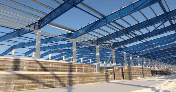 Moderna construcción de almacén, la estructura estructural de acero de un nuevo edificio comercial contra un cielo azul claro en el fondo, la construcción de una fábrica o almacén moderno — Vídeo de stock