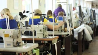 Çalışan bir dikiş makinesi, endüstriyel boyutu tekstil fabrikası, işçilerin üretim hattı, sanayi iç, iğne dikiş makinesi, sığ derinlik-in tarla, kadın