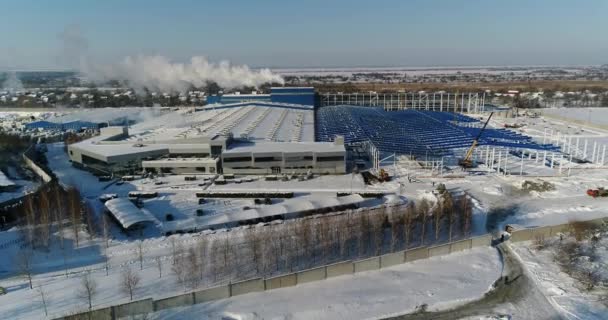 Egy modern gyár vagy kereskedelmi épület, külső részén egy modern gyár vagy növény, épület homlokzat és a parkoló, panorámás kilátás a levegőből, téli időben, napsütésben, kék ég — Stock videók