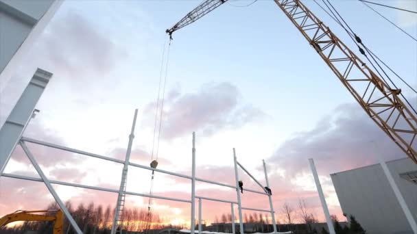 Exterior industrial, Montaje de estructuras metálicas sobre el fondo de un cielo anaranjado con nubes, trabajos de construcción, construcción de un edificio industrial, timelapse — Vídeos de Stock