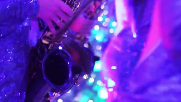 Une fille avec un saxophone, un groupe musical de filles avec un saxophone se produisent sur scène, une robe bleue, une lumière de scène, un mouvement, gros plan, boîte de nuit, restaurant 