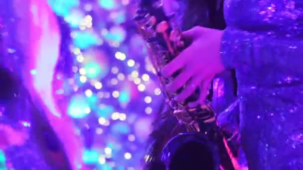 Une fille avec un saxophone, un groupe musical de filles avec un saxophone se produisent sur scène, une robe bleue, une lumière de scène, un mouvement, gros plan, boîte de nuit, restaurant 