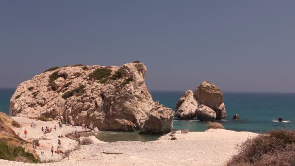 La gente si bagna e prende il sole su una piccola spiaggia di sabbia, il luogo di nascita di Afrodite sull'isola di Cipro, Rocce sporgono dall'acqua del mare, Bella spiaggia nel Mar Mediterraneo, spiaggia rocciosa — Video Stock