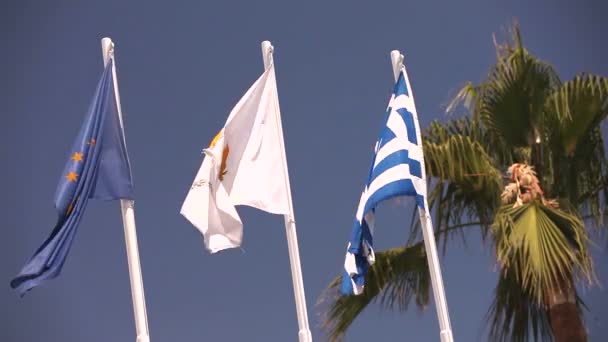 Banderas de la Unión Europea, Grecia, Chipre, la ciudad de Aya Napa, Grecia, Banderas en el asta de la bandera, el viento ondeando la bandera, Banderas en el asta de la bandera, la bandera ondeando viento, contra el fondo del cielo azul — Vídeos de Stock
