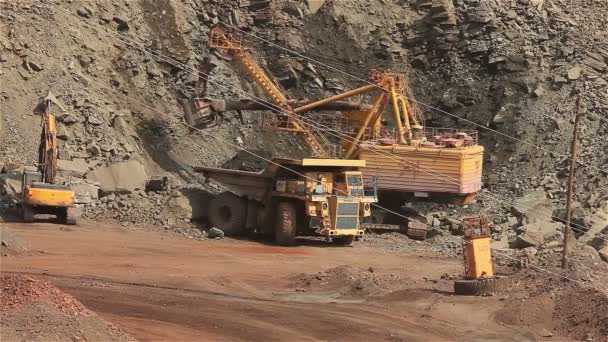 De graafmachine en dumper in de steengroeve, grote gele graafmachine erts in een dumper geladen — Stockvideo