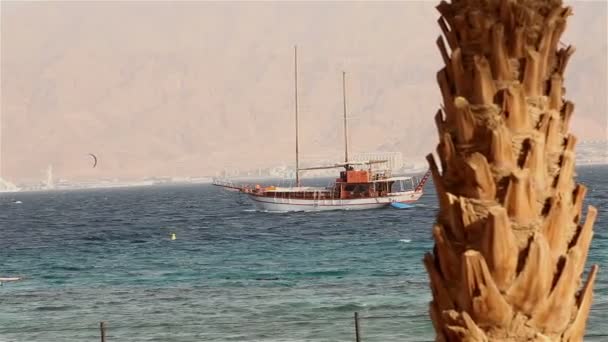 Nave a vela galleggia in mare, yacht a vela, passeggiata in mare su uno yacht a vela, silhouette di yacht solitario senza vele e con persone all'orizzonte con tempo soleggiato — Video Stock