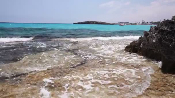 Лазурне море, море берга кольорове, хвилі ламаються на скелястому березі, на тлі берегової лінії — стокове відео