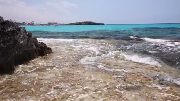 Il mare azzurro, un mare di colore berg, le onde si infrangono contro la riva rocciosa, sullo sfondo della linea costiera — Video Stock