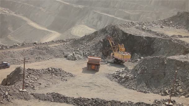 La excavadora y el dumper en la cantera, excavadora amarilla grande cargó el mineral en un dumper, exterior industrial — Vídeos de Stock