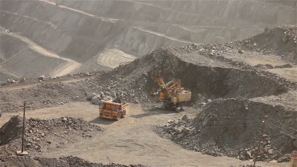 La excavadora y el dumper en la cantera, excavadora amarilla grande cargó el mineral en un dumper, exterior industrial — Vídeo de stock