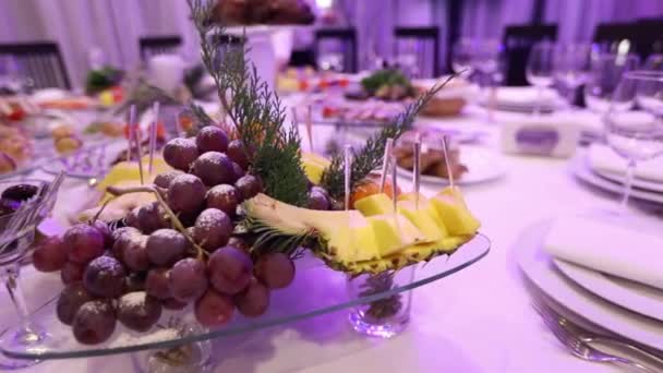 Fruta y comida en la mesa del banquete en el restaurante, trozos de piña y racimos de uvas en la mesa del banquete, decoración de la sala de banquetes, interior del restaurante — Vídeos de Stock