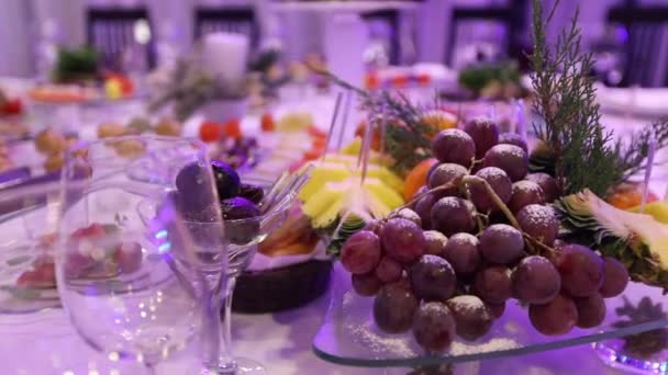 Fruta e comida na mesa do banquete no restaurante, pedaços de abacaxi e cachos de uvas na mesa do banquete, decoração do salão do banquete, interior do restaurante — Vídeo de Stock