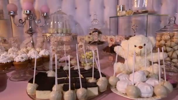 Bar de doces no restaurante, festa infantil, um urso de pelúcia branco com uma borboleta no pescoço, vela acesa, ursinho de pelúcia em uma mesa Bar de doces, close-up, design de barra de doces, design Bar de doces — Vídeo de Stock