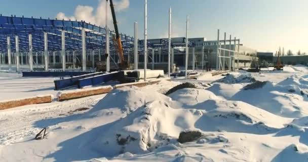 Construção de uma fábrica ou planta moderna, área industrial no inverno, vista panorâmica do ar. Planta moderna no campo coberto de neve, a estrutura de aço estrutural de um novo edifício comercial — Vídeo de Stock