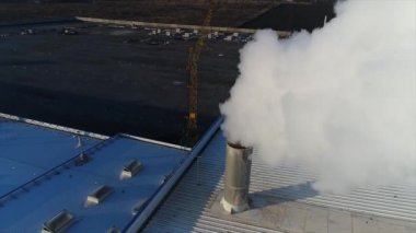 bir fabrika veya fabrika çatısında bir borudan duman, çatıya bir boru, beyaz kalın duman ile üretim odası boru çıkar