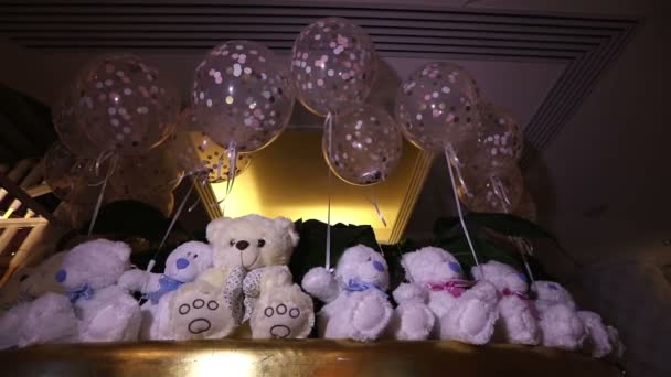 Teddy bears sedí v řadě, bílými medvídky, helium balónky, roztomilý medvídek s motýlkem na její krk, Plyšová hračka, interiéru haly pro dětské narozeniny, dárek, místnosti a interiéru, Medvídek — Stock video