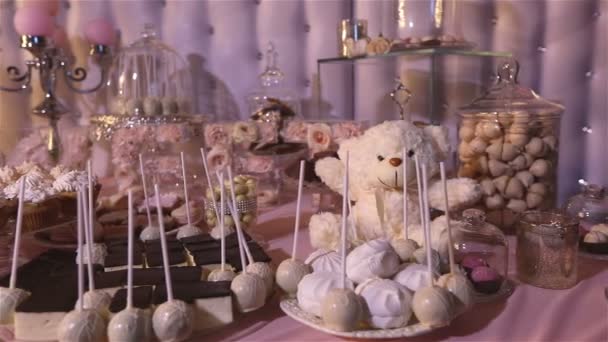 Кэнди-бар в ресторане, детская вечеринка, белый плюшевый мишка с бабочкой на шее, зажженная свеча, плюшевый мишка на столе Кэнди-бар, крупный план, дизайн Кэнди-бара, дизайн Кэнди-бара — стоковое видео